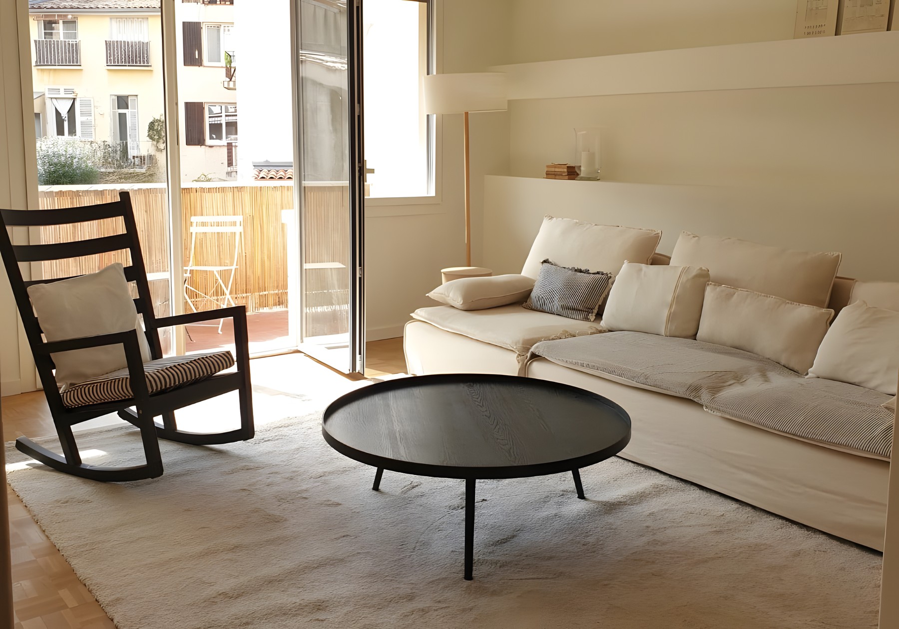 Salon clair avec canapé en lin, fauteuil à bascule et table basse noire