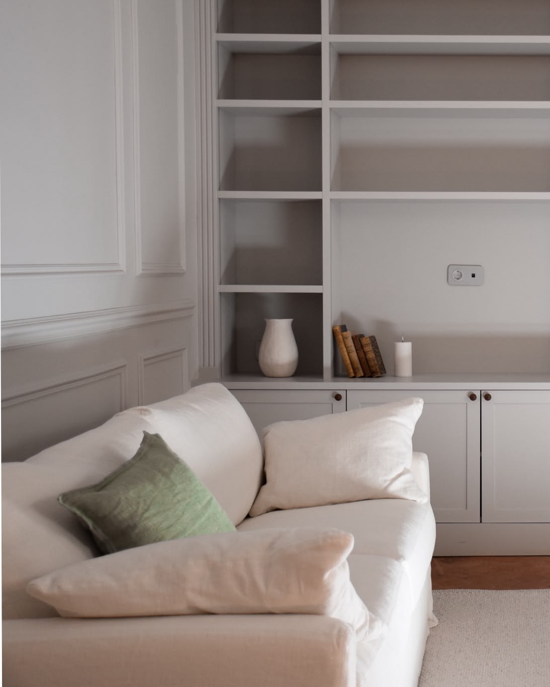 Salon d'un appartement bourgeois à Aix-en-Provence, canapé en lin blanc, coussin vert sauge et bibliothèque sur mesure peinte en gris